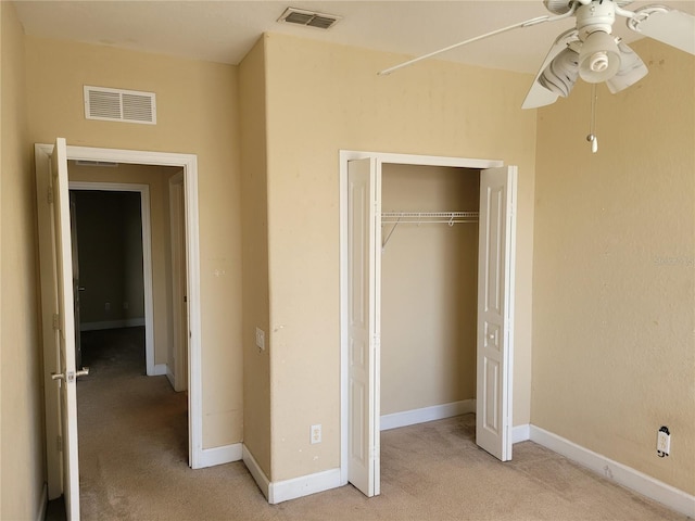 unfurnished bedroom with light colored carpet, a closet, baseboards, and a ceiling fan