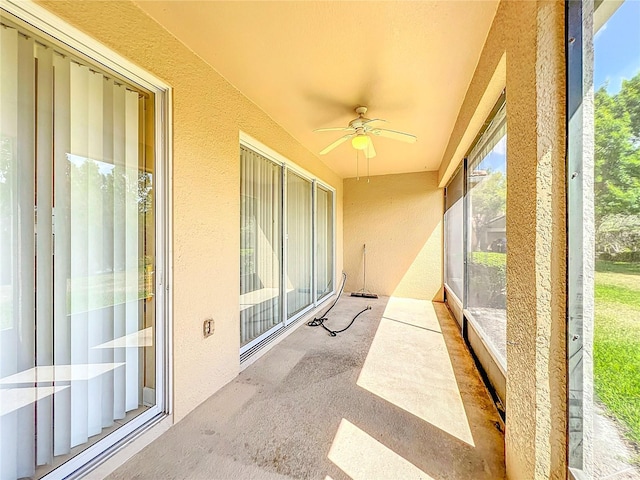 unfurnished sunroom with a textured wall, a ceiling fan, and carpet floors