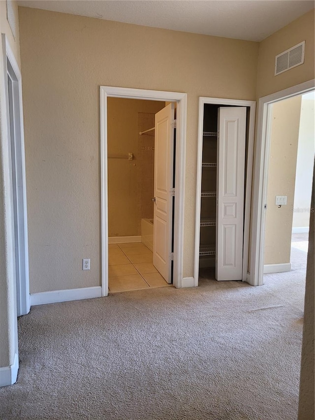 unfurnished bedroom featuring carpet floors, baseboards, a closet, and connected bathroom