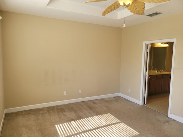 empty room featuring light colored carpet, ceiling fan, and baseboards