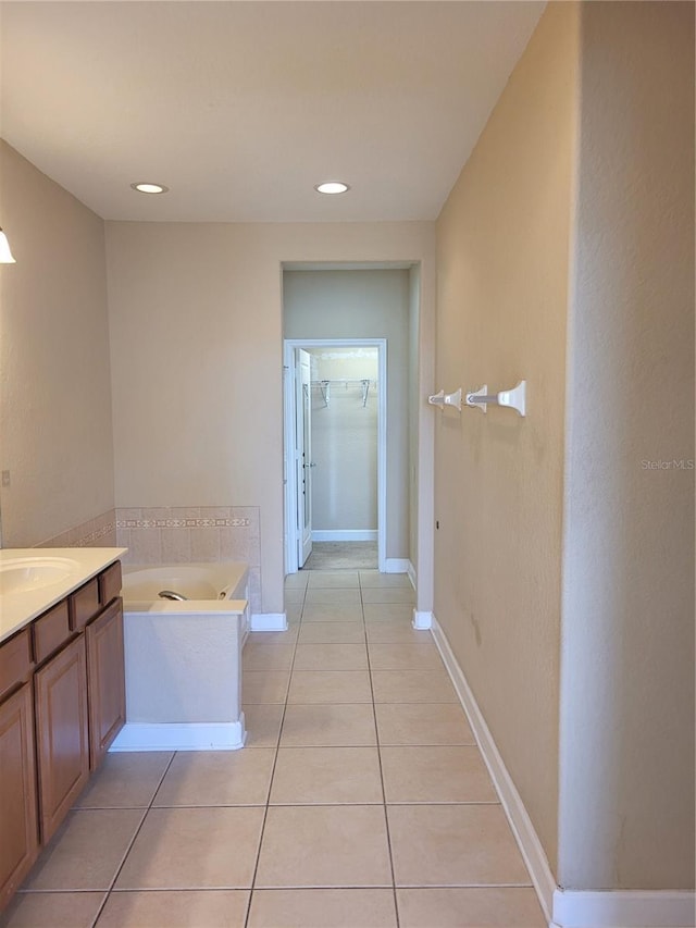 bathroom with tile patterned flooring, a garden tub, vanity, baseboards, and recessed lighting