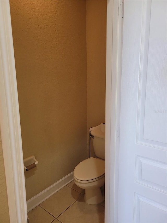 bathroom with tile patterned flooring, toilet, and baseboards