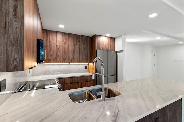 kitchen with a sink, modern cabinets, and light stone countertops