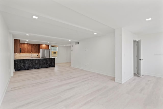 unfurnished living room with a sink, baseboards, light wood-style floors, and recessed lighting