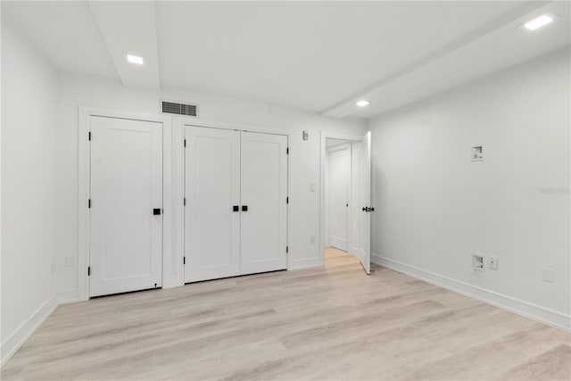 unfurnished bedroom featuring baseboards, light wood-style flooring, and visible vents