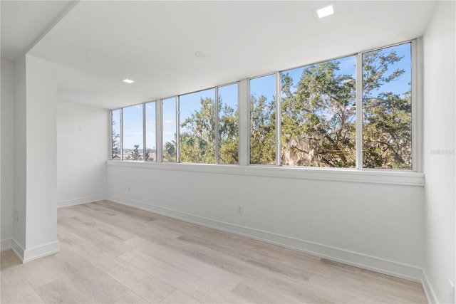 spare room featuring baseboards and light wood-style floors