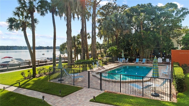 community pool featuring a yard, a water view, fence, and a patio area