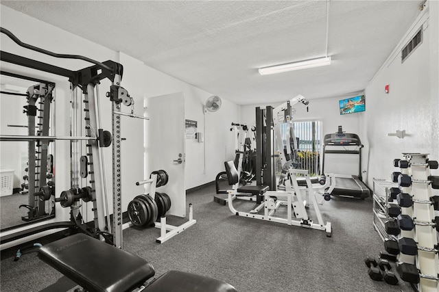 gym with baseboards, visible vents, and a textured ceiling