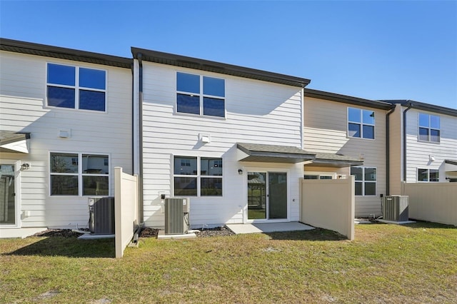 rear view of house featuring central AC unit, a lawn, and fence