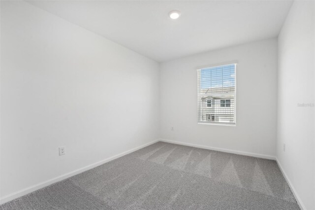 carpeted spare room featuring baseboards