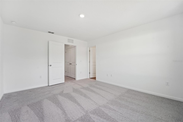 unfurnished room featuring light colored carpet, visible vents, and baseboards