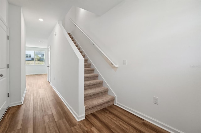 stairway with baseboards, wood finished floors, and recessed lighting
