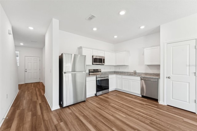 kitchen featuring visible vents, white cabinets, wood finished floors, and appliances with stainless steel finishes