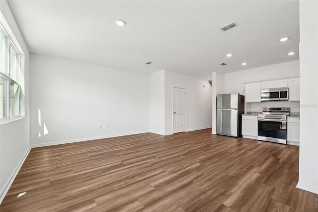 unfurnished living room with baseboards, visible vents, wood finished floors, and recessed lighting
