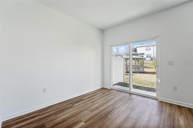 unfurnished room with baseboards and wood finished floors