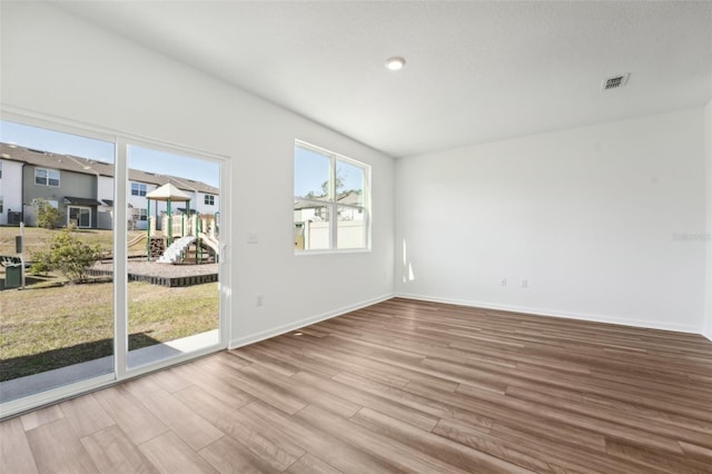 spare room with baseboards, visible vents, and wood finished floors