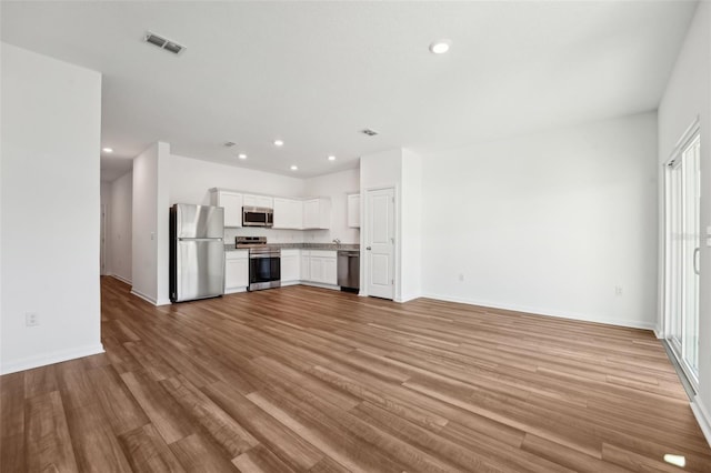 unfurnished living room featuring baseboards, visible vents, recessed lighting, and light wood-type flooring