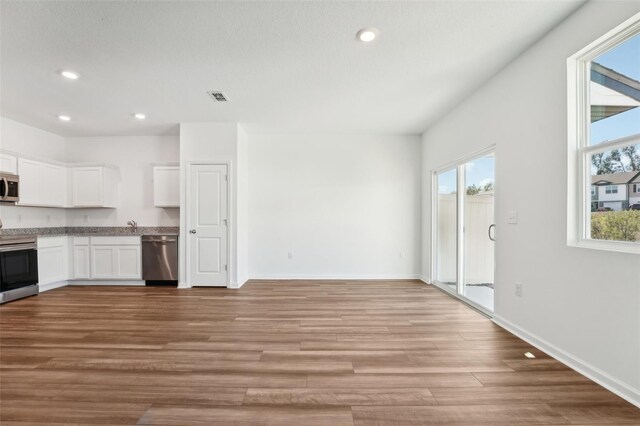 kitchen with plenty of natural light, light wood-type flooring, white cabinets, and appliances with stainless steel finishes