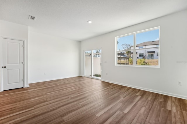unfurnished room featuring baseboards, visible vents, and wood finished floors