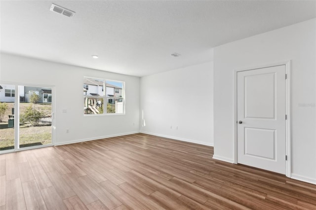 spare room with baseboards, visible vents, wood finished floors, and a textured ceiling