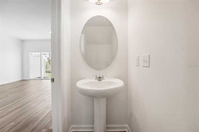 bathroom with baseboards, wood finished floors, and a sink