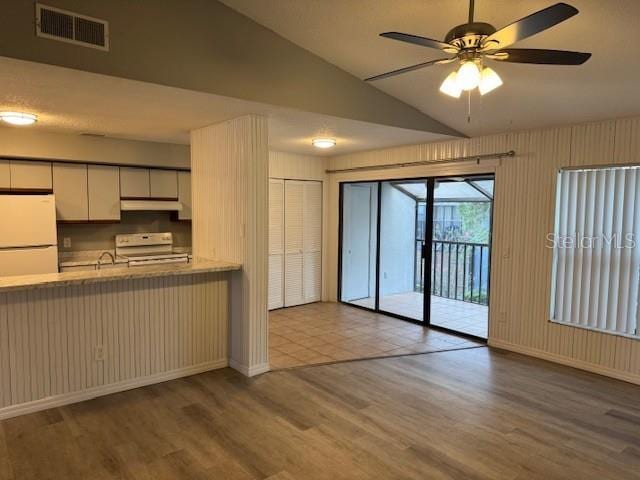 4706 Sutton Ter Unit 111A2, Orlando, FL 32811 - kitchen with freestanding refrigerator, wood finished floors, range with electric stovetop, vaulted ceiling, and a ceiling fan
