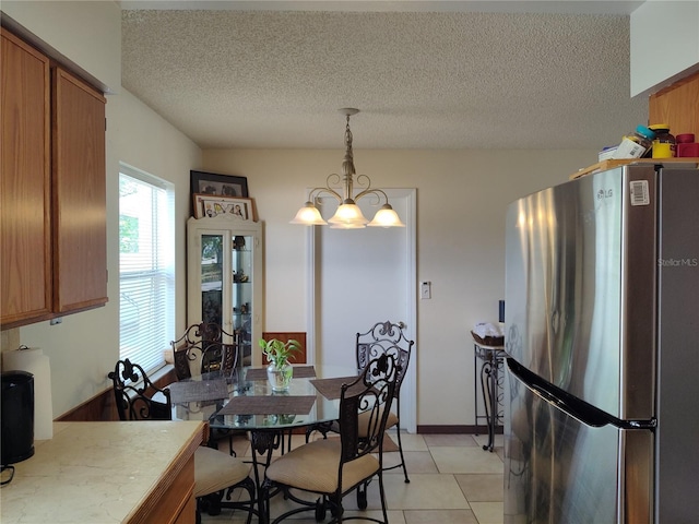 dining space with a textured ceiling, an inviting chandelier, and light tile patterned floors