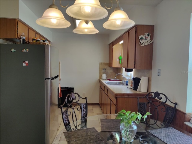 kitchen with a sink, freestanding refrigerator, and brown cabinetry