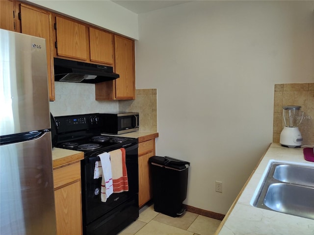 kitchen with under cabinet range hood, appliances with stainless steel finishes, decorative backsplash, and light countertops