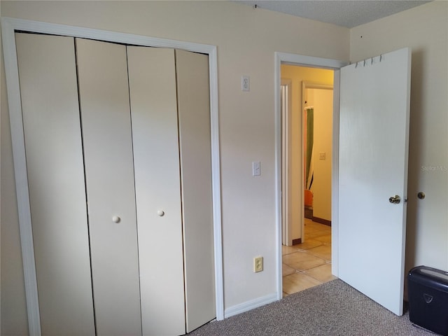 unfurnished bedroom featuring a closet, baseboards, and light carpet