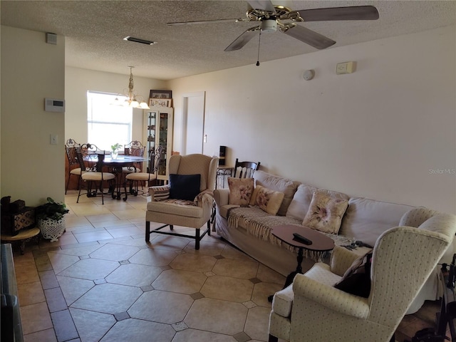living area with a textured ceiling, visible vents, and ceiling fan with notable chandelier