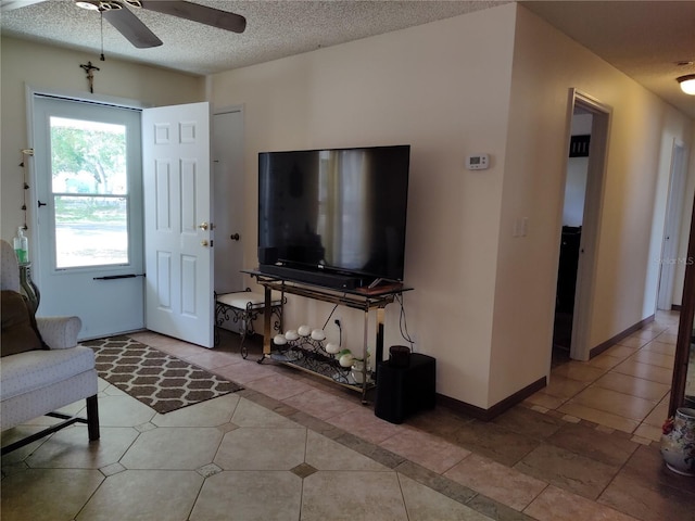 tiled living area featuring baseboards, ceiling fan, and a textured ceiling