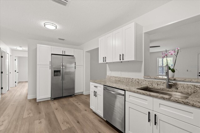 4246 Clarinda St, Orlando, FL 32811 - kitchen with white cabinetry, a sink, stainless steel appliances, and light wood-type flooring