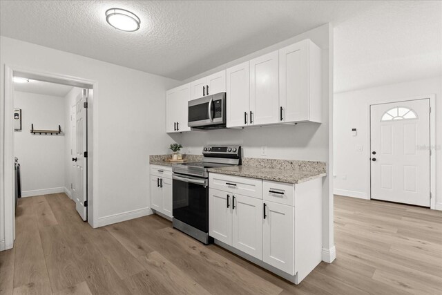 4246 Clarinda St, Orlando, FL 32811 - kitchen featuring baseboards, white cabinets, light wood-type flooring, and appliances with stainless steel finishes
