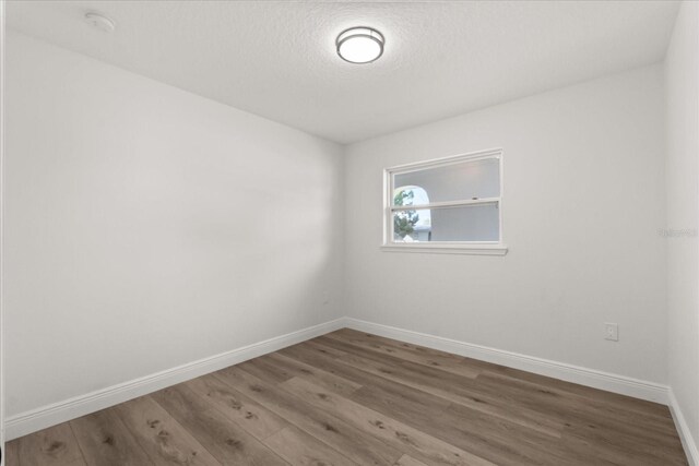 4246 Clarinda St, Orlando, FL 32811 - empty room featuring baseboards, wood finished floors, and a textured ceiling