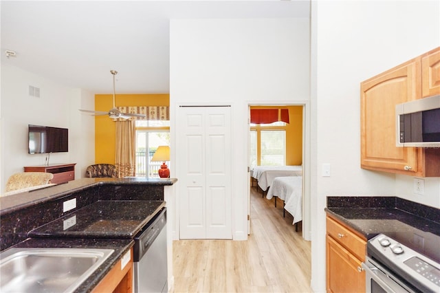 8100 Poinciana Blvd Unit 2109, Orlando, FL 32821 - kitchen with appliances with stainless steel finishes, open floor plan, dark stone countertops, visible vents, and light wood-style floors