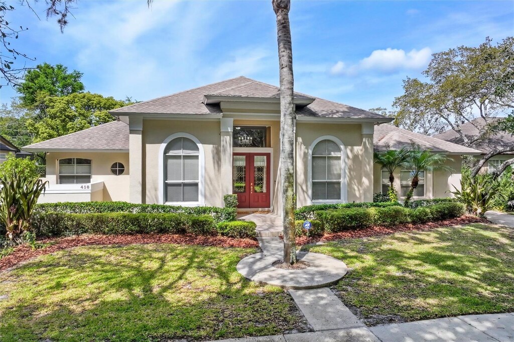 418 Curry Ct, Altamonte Springs, FL 32714 - view of front of house featuring a front lawn, stucco siding, french doors, and roof with shingles