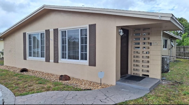 view of home's exterior featuring central air condition unit, fence, and stucco siding
