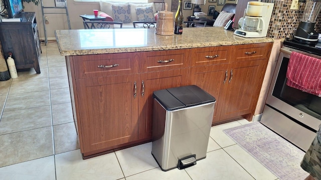 details with brown cabinetry, electric range, a peninsula, tasteful backsplash, and light stone counters