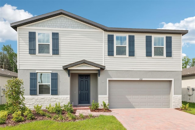 4705 Jasmine Cir, Leesburg, FL 34748 - view of front facade with decorative driveway, an attached garage, stone siding, and stucco siding
