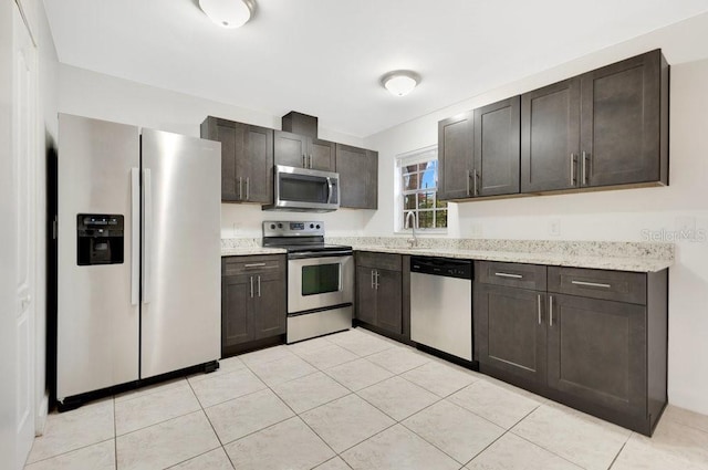 5763 Saint Christopher Dr Unit 55, Orlando, FL 32822 - kitchen featuring light tile patterned floors, dark brown cabinetry, appliances with stainless steel finishes, light stone counters, and a sink