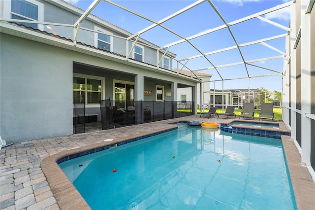 view of swimming pool featuring a patio, a pool with connected hot tub, and glass enclosure