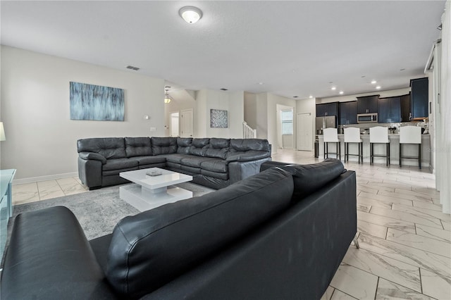 living room with light marble finish flooring, baseboards, recessed lighting, and stairs