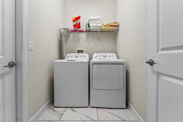 laundry area with washing machine and clothes dryer, light marble finish floors, and baseboards