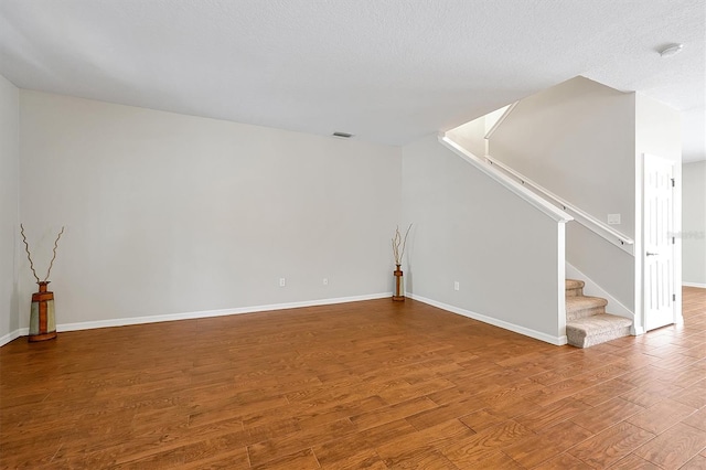 unfurnished living room featuring stairs, baseboards, visible vents, and wood finished floors