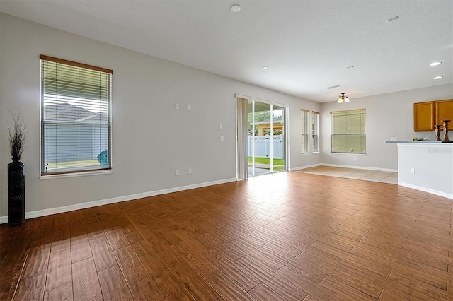 unfurnished living room featuring recessed lighting, baseboards, and light wood-type flooring