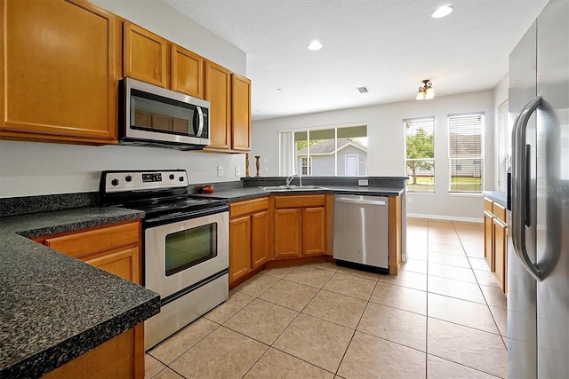 kitchen with a sink, stainless steel appliances, recessed lighting, a peninsula, and light tile patterned floors