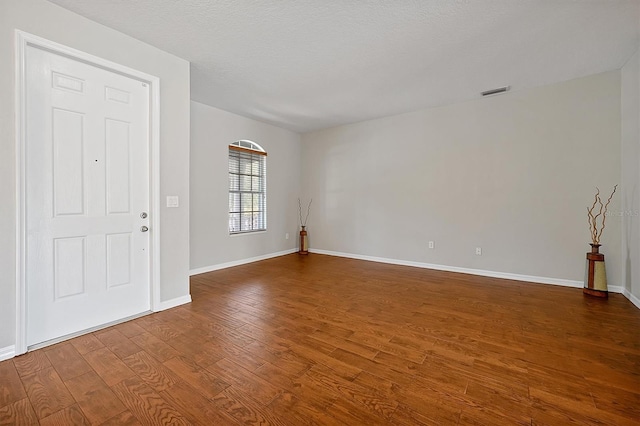 unfurnished room featuring baseboards, wood finished floors, and visible vents