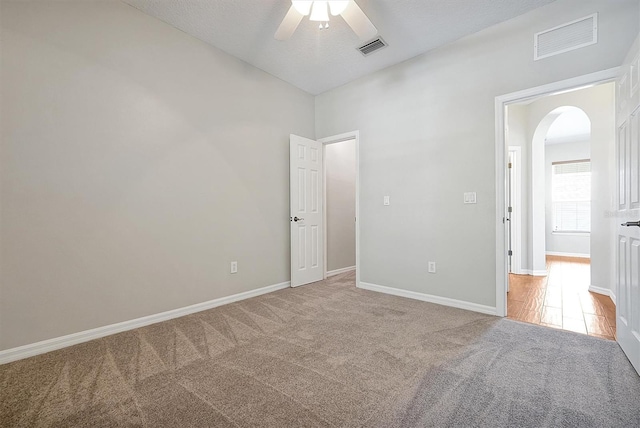 unfurnished bedroom with arched walkways, baseboards, carpet, and visible vents