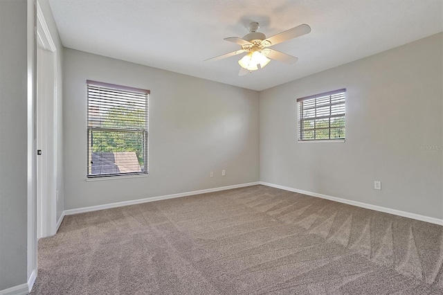 carpeted spare room with baseboards and a ceiling fan